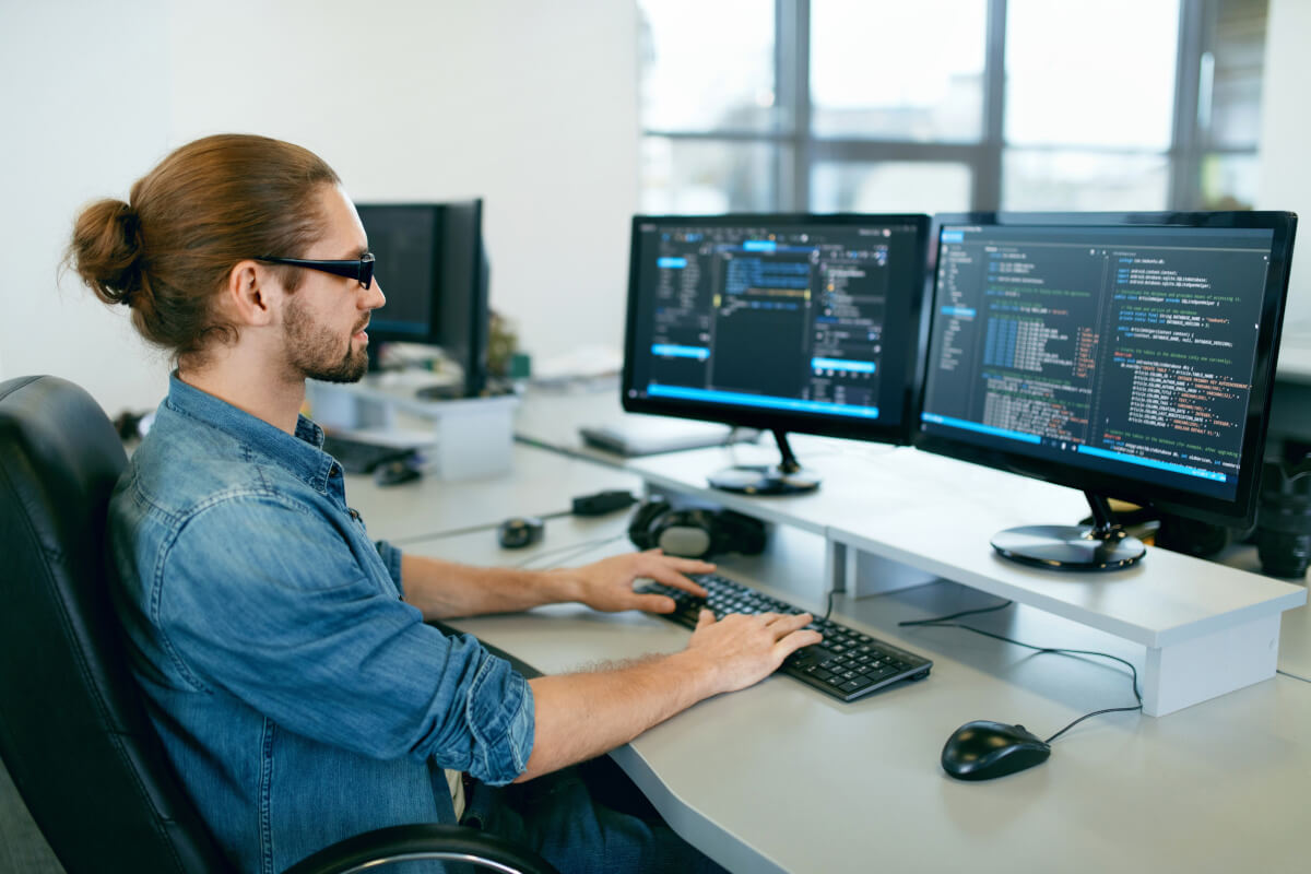 Male technician at desk using a two monitor display